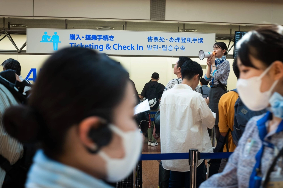 An ANA staffer uses a megaphone in the departure lobby of Haneda Airport in August 2024. An ANA staffer uses a megaphone in the departure lobby of Haneda Airport in August 2024.