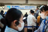 An ANA staffer uses a megaphone in the departure lobby of Haneda Airport in August 2024. | Bloomberg