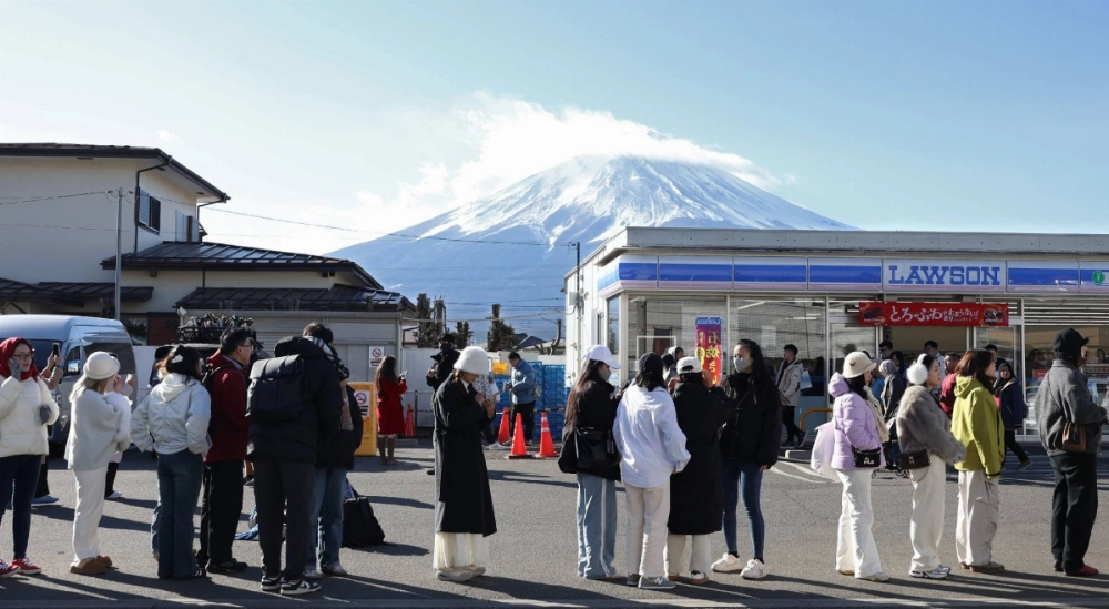 Visitors line up to take photos in front of a convenience store with Mount Fuji in the background at the town of Fujikawaguchiko, Yamanashi Prefecture, on Jan. 29. Visitors line up to take photos in front of a convenience store with Mount Fuji in the background at the town of Fujikawaguchiko, Yamanashi Prefecture, on Jan. 29.