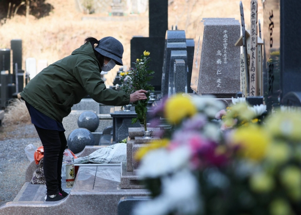 A woman visits a grave in Rikuzentakata, Iwate Prefecture, on Tuesday on the 14th anniversary of the Great East Japan Earthquake. Populations in the hardest hit prefectures of Iwate, Miyagi and Fukushima are sharply falling. A woman visits a grave in Rikuzentakata, Iwate Prefecture, on Tuesday on the 14th anniversary of the Great East Japan Earthquake. Populations in the hardest hit prefectures of Iwate, Miyagi and Fukushima are sharply falling.