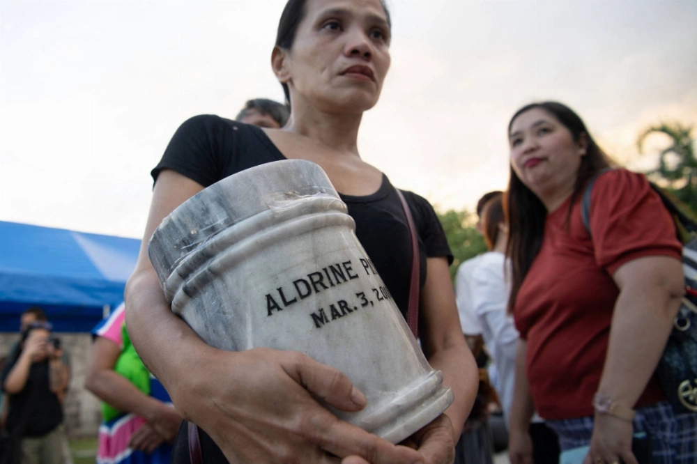 A woman clutches an urn containing the ashes of a loved one during a funeral ceremony for victims of former Philippine President Rodrigo Duterte's war on drugs, at a cemetery in Manila on Wednesday, the day after his arrest. A woman clutches an urn containing the ashes of a loved one during a funeral ceremony for victims of former Philippine President Rodrigo Duterte's war on drugs, at a cemetery in Manila on Wednesday, the day after his arrest.