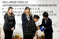 Then-Foreign Minister Yoko Kamikawa presents a gift to a Ukrainian refugee during the Women, Peace and Security session as part of the Japan-Ukraine Conference for Promotion of Economic Growth and Reconstruction at the Japan Business Federation in February last year.   | Pool / via REUTERS