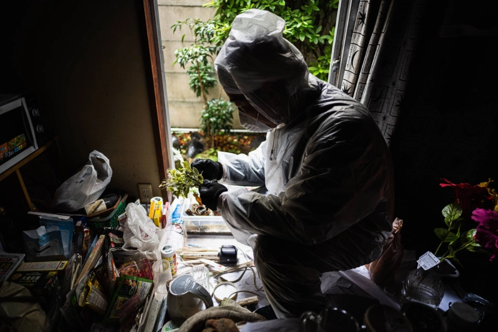 Professional cleaner Hirofumi Sakurai takes a moment to appreciate some photographs in a Gotanda apartment whose occupant died alone. Professional cleaner Hirofumi Sakurai takes a moment to appreciate some photographs in a Gotanda apartment whose occupant died alone.