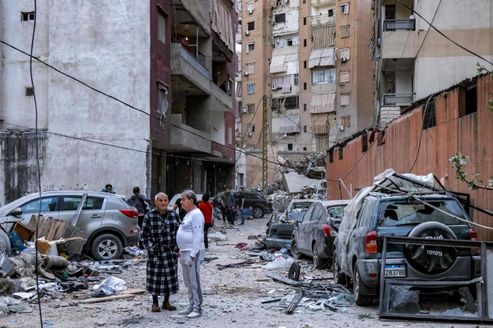 Men stand at the scene of an Israeli strike in Beirut's southern suburbs on Tuesday. Men stand at the scene of an Israeli strike in Beirut's southern suburbs on Tuesday.
