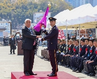 At the launch ceremony on Sunday of the Self-Defense Forces Maritime Transport Group in Kure City, Hiroshima Prefecture, Defense Minister Gen Nakatani presents the unit's group flag. | JIJI