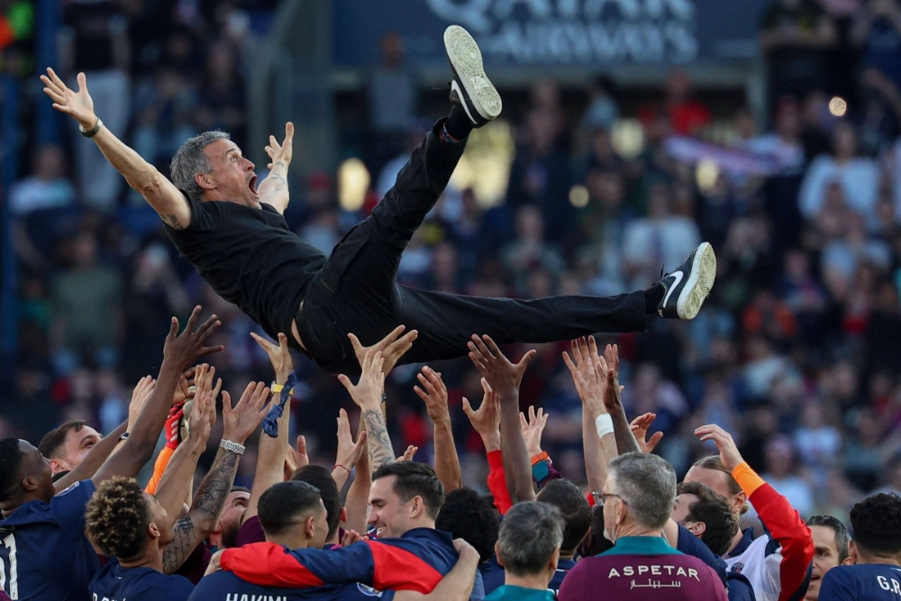 Paris Saint-Germain's players throw coach Luis Enrique into the air as they celebrate winning the French league title in Paris on Saturday. Paris Saint-Germain's players throw coach Luis Enrique into the air as they celebrate winning the French league title in Paris on Saturday.