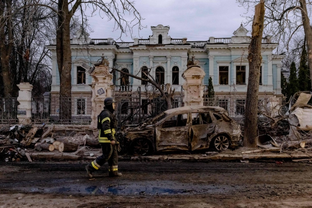 A Ukrainian rescuer walks by a burned car in front of damaged building at the site of a missile attack in Sumy, northeastern Ukraine, on Sunday.  A Ukrainian rescuer walks by a burned car in front of damaged building at the site of a missile attack in Sumy, northeastern Ukraine, on Sunday.