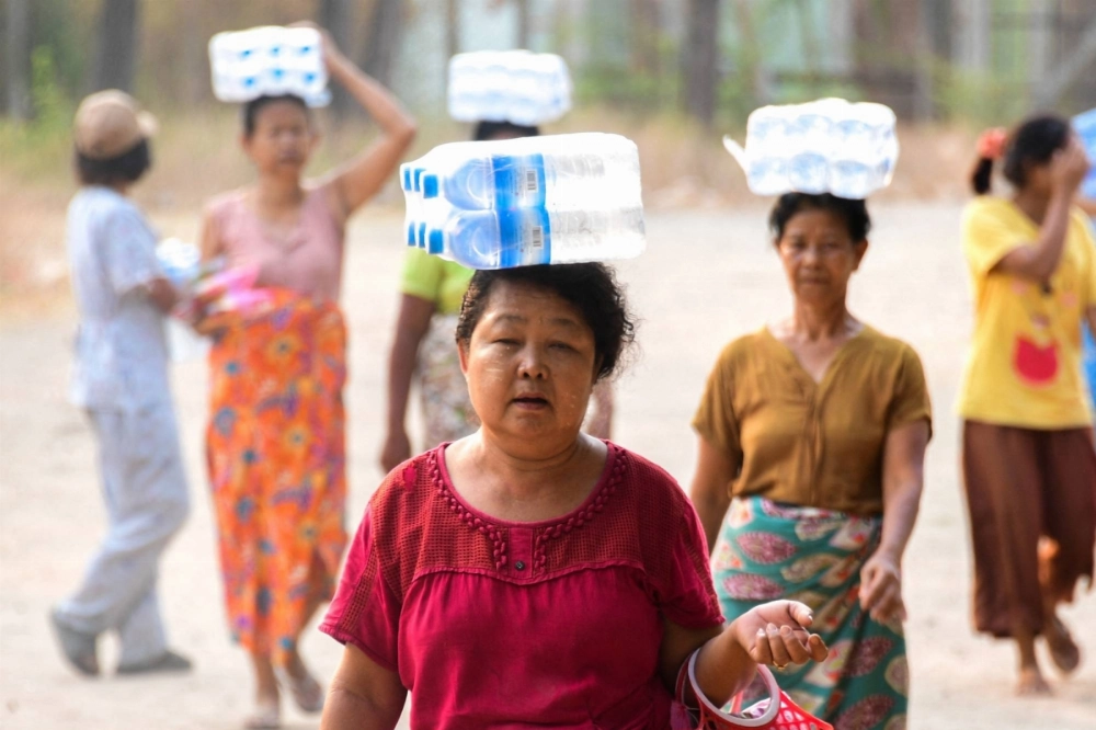 People carry packs of bottles of water following a strong earthquake in Pyawbwe township, Mandalay, Myanmar, on April 4. People carry packs of bottles of water following a strong earthquake in Pyawbwe township, Mandalay, Myanmar, on April 4.