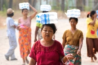 People carry packs of bottles of water following a strong earthquake in Pyawbwe township, Mandalay, Myanmar, on April 4. | Reuters