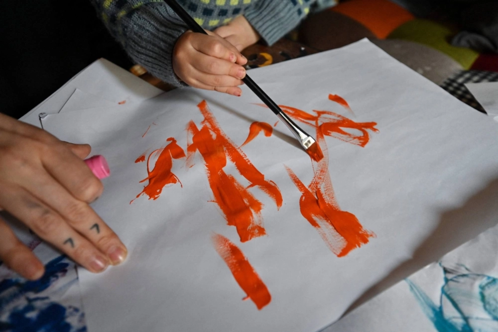 A 21-month-old artist who goes by the name "Thumbelina" uses a brush to paint alongside her mother at the family's home in Tokyo.  A 21-month-old artist who goes by the name "Thumbelina" uses a brush to paint alongside her mother at the family's home in Tokyo.