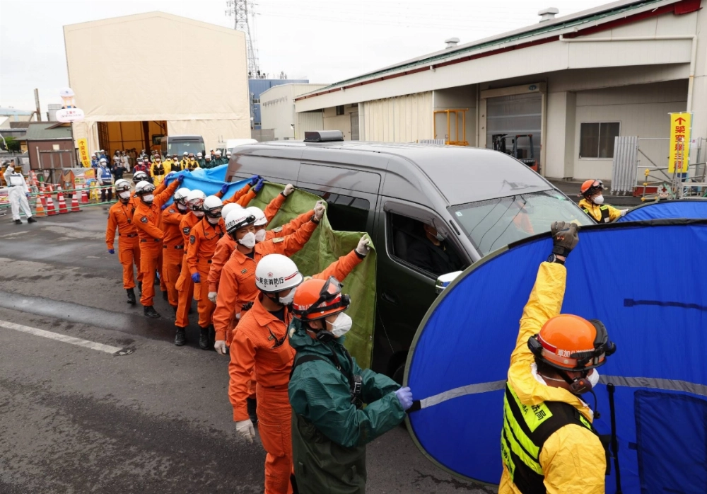 Workers stand around a vehicle carrying the body of a person recovered from a sinkhole in Yashio, Saitama Prefecture, on Friday. Workers stand around a vehicle carrying the body of a person recovered from a sinkhole in Yashio, Saitama Prefecture, on Friday.
