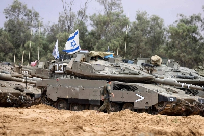 An Israeli soldier walks near tanks deployed at a position near Israel's border with the Gaza Strip on Sunday. An Israeli soldier walks near tanks deployed at a position near Israel's border with the Gaza Strip on Sunday.