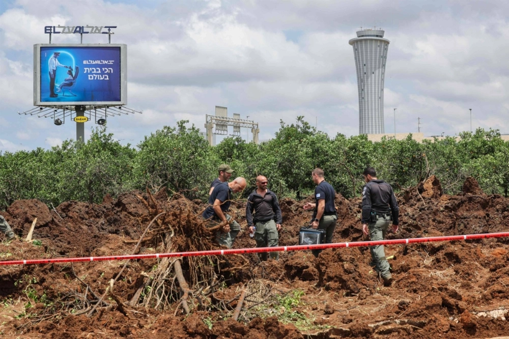 Members of Israeli security services inspect a crater near a road outside Israel's Ben Gurion airport after a missile launched from Yemen struck the area on Sunday.  Members of Israeli security services inspect a crater near a road outside Israel's Ben Gurion airport after a missile launched from Yemen struck the area on Sunday.