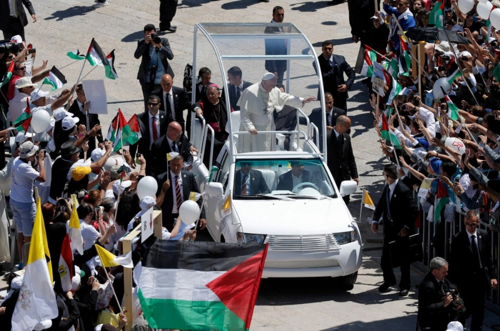 Pope Francis waves to the crowd from his popemobile as he arrives at the Manger Square before presiding over an open-air mass on May 25, 2014 outside the Church of the Nativity in the West Bank Biblical town of Bethlehem.  Pope Francis waves to the crowd from his popemobile as he arrives at the Manger Square before presiding over an open-air mass on May 25, 2014 outside the Church of the Nativity in the West Bank Biblical town of Bethlehem.