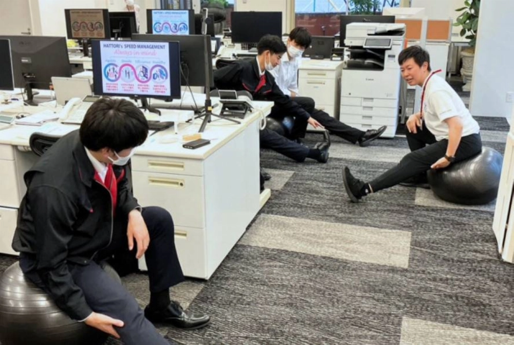 A public health nurse (right) teaches stretching techniques using an exercise ball to employees of Hattori, a machine tool and industrial equipment supplier in Aichi Prefecture. A public health nurse (right) teaches stretching techniques using an exercise ball to employees of Hattori, a machine tool and industrial equipment supplier in Aichi Prefecture.
