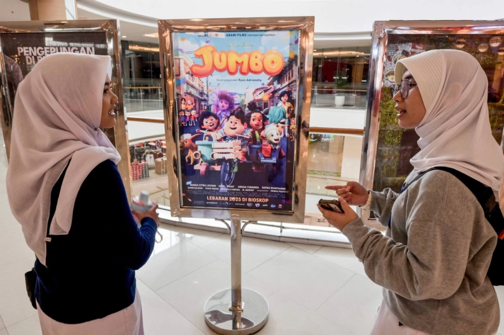 Two teenagers stand in front of a poster for "Jumbo" at a cinema in Bekasi, West Java.  Two teenagers stand in front of a poster for "Jumbo" at a cinema in Bekasi, West Java.