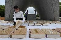 A city government official airs out the register of people who died as a result of the U.S. atomic bombing of Hiroshima on Thursday for its upkeep in the Hiroshima Peace Memorial Park | Jiji