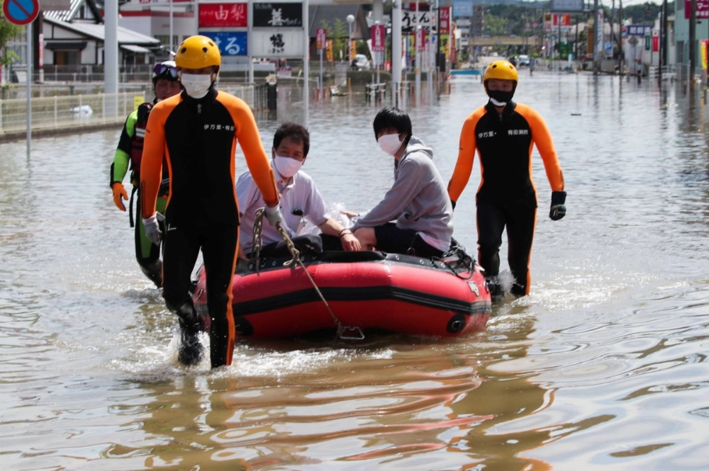 Rescue workers transport people using a raft along a flooded street in Takeo, Saga Prefecture, in August 2021. Rescue workers transport people using a raft along a flooded street in Takeo, Saga Prefecture, in August 2021.