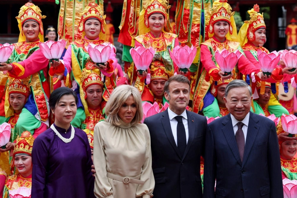 Vietnam Communist Party General Secretary To Lam (right), his wife Ngo Phong Ly (left), French President Emmanuel Macron (second from right) and his wife Brigitte Macron pose for a picture with traditional dance performers during a luncheon at the Temple of Literature in Hanoi on Monday. Vietnam Communist Party General Secretary To Lam (right), his wife Ngo Phong Ly (left), French President Emmanuel Macron (second from right) and his wife Brigitte Macron pose for a picture with traditional dance performers during a luncheon at the Temple of Literature in Hanoi on Monday.