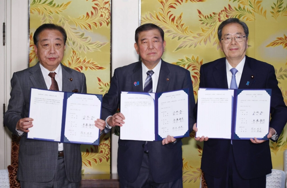 The leaders of the main opposition Constitutional Democratic Party of Japan and the ruling Liberal Democratic Party-Komeito bloc hold up a document on their agreement to reform the pension system in Tokyo on Tuesday. The leaders of the main opposition Constitutional Democratic Party of Japan and the ruling Liberal Democratic Party-Komeito bloc hold up a document on their agreement to reform the pension system in Tokyo on Tuesday.