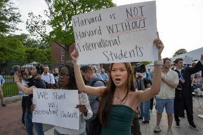 People hold up signs during a rally in support of international students at the Harvard University campus in Boston on Tuesday. People hold up signs during a rally in support of international students at the Harvard University campus in Boston on Tuesday.