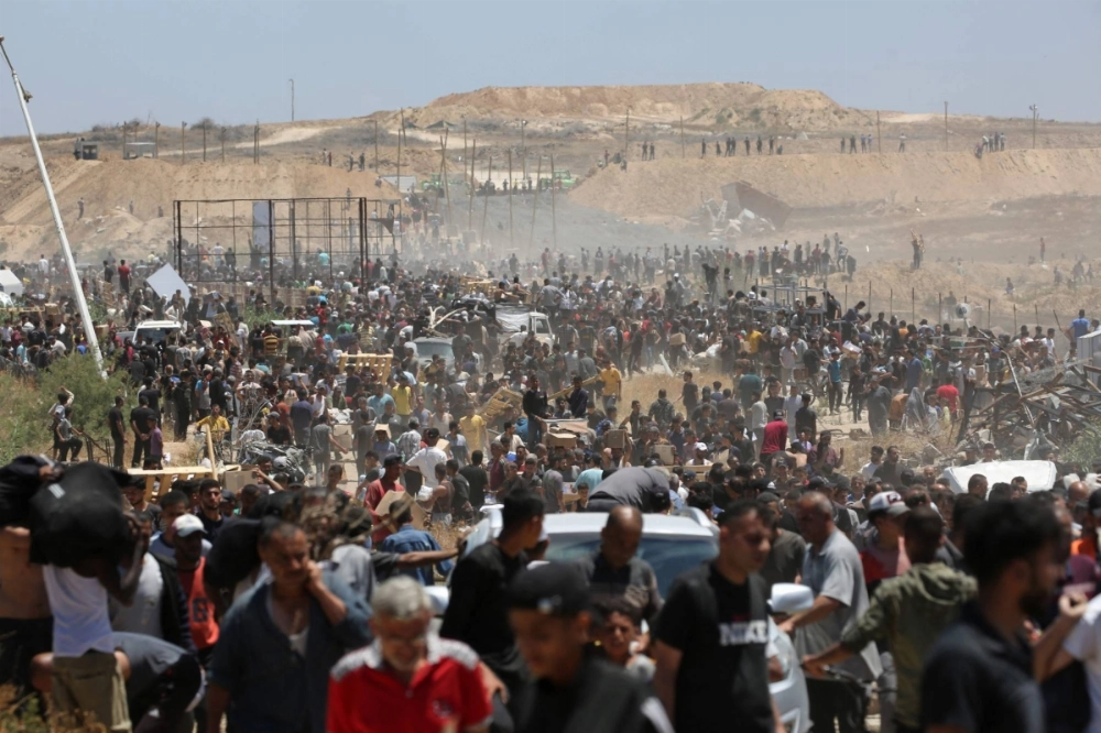 Displaced Palestinians carrying relief supplies return from an aid distribution center in the central Gaza Strip on Thursday. Displaced Palestinians carrying relief supplies return from an aid distribution center in the central Gaza Strip on Thursday.