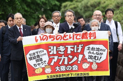 Plaintiffs who filed a lawsuit seeking welfare benefit cuts to be revoked and their lawyers walk to the Supreme Court in Tokyo on May 27. Plaintiffs who filed a lawsuit seeking welfare benefit cuts to be revoked and their lawyers walk to the Supreme Court in Tokyo on May 27.