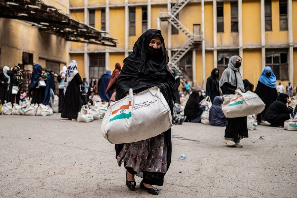 An Afghan woman carries away food aid donated by the Indian government in Kabul on May 18. An Afghan woman carries away food aid donated by the Indian government in Kabul on May 18.