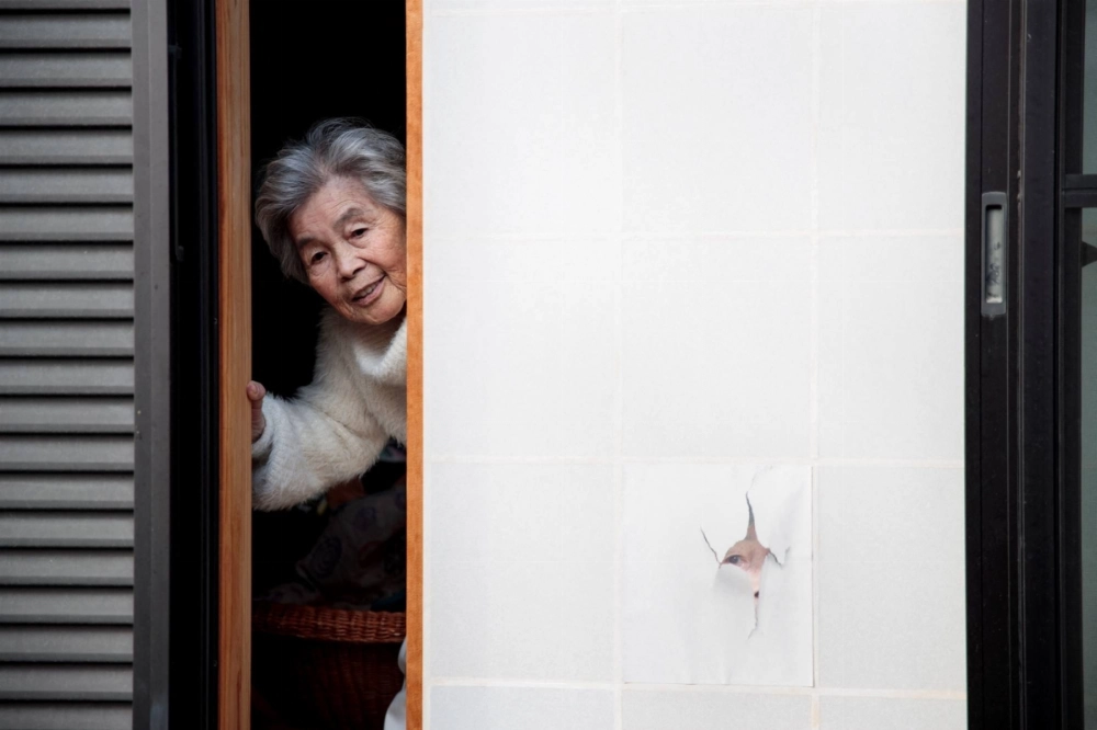 Kimiko Nishimoto poses next to a picture of her on a sliding window at her house in the city of Kumamoto in January 2018. Kimiko Nishimoto poses next to a picture of her on a sliding window at her house in the city of Kumamoto in January 2018.