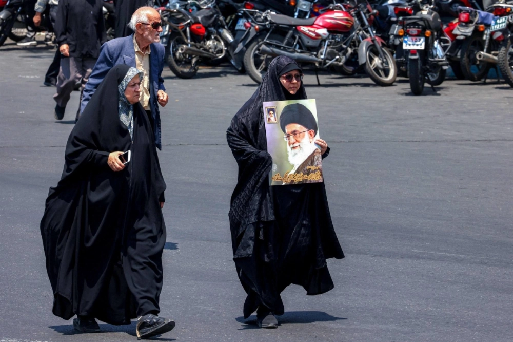 A woman walks with a sign depicting Iranian Supreme Leader Ayatollah Ali Khamenei as people gather for a protest against Israel's wave of strikes on Iran in central Tehran on Friday. A woman walks with a sign depicting Iranian Supreme Leader Ayatollah Ali Khamenei as people gather for a protest against Israel's wave of strikes on Iran in central Tehran on Friday.