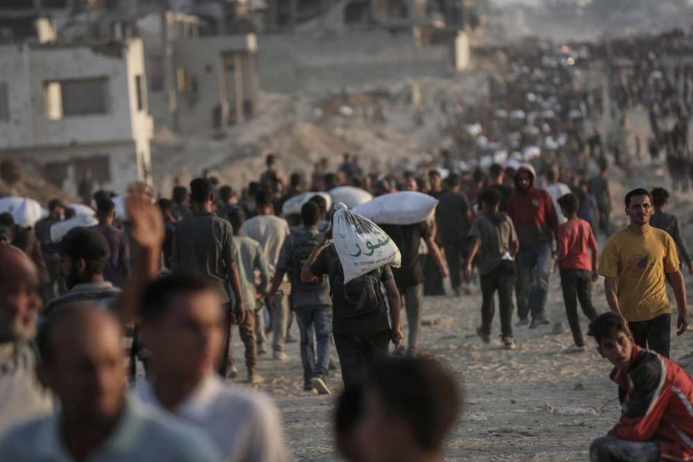 Palestinians carry sacks of flour collected from an aid distribution point in Beit Lahia, northern Gaza, on Tuesday. Palestinians carry sacks of flour collected from an aid distribution point in Beit Lahia, northern Gaza, on Tuesday.