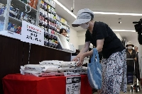 A customer picks up a bag of government-stockpiled rice sold at a convenience store in Tokyo. | Jiji
