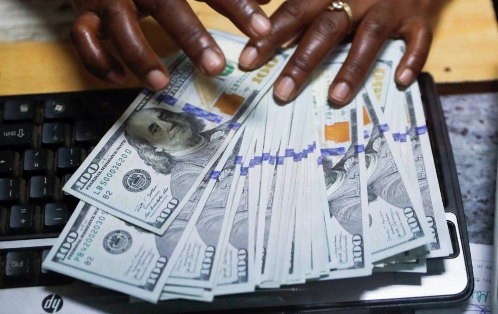 A teller sorts U.S. banknotes inside the cashier's booth at a foreign exchange bureau in downtown Nairobi in 2024. A teller sorts U.S. banknotes inside the cashier's booth at a foreign exchange bureau in downtown Nairobi in 2024.