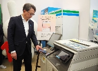 Digital transformation minister Masaaki Taira obtains a certification document using a My Number personal identification card installed on an iPhone in Tokyo on Tuesday. | Jiji
