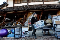 A resident carries his belongings from his damaged house in Nanao, Ishikawa Prefecture, on Jan. 2, 2024 — the day after a major earthquake devastated parts of the area. | Reuters