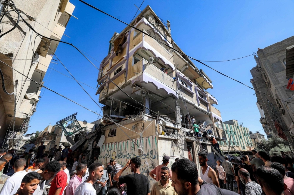 People gather outside a building that was hit by Israeli bombardment in the Nuseirat camp for Palestinian refugees in the central Gaza Strip on Sunday. People gather outside a building that was hit by Israeli bombardment in the Nuseirat camp for Palestinian refugees in the central Gaza Strip on Sunday.