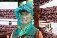 Jung Yong-sun, a local official tasked with pest-control duties, poses while wearing a plastic netted onion bag for protection from "lovebugs" on the peak of Gyeyangsan Mountain in Incheon, west of Seoul.  | AFP-JIJI