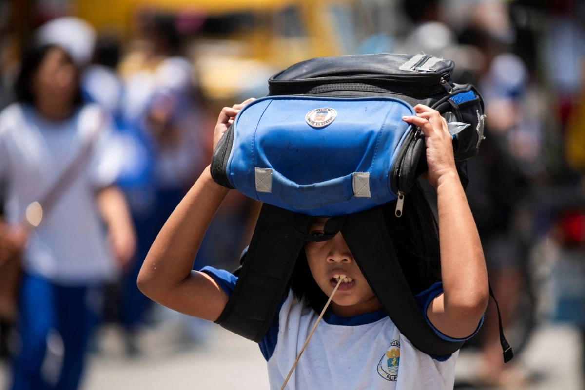 A student uses her bag as protection against the sun outside an elementary school in Manila in April 2024. A student uses her bag as protection against the sun outside an elementary school in Manila in April 2024.