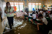 A public school teacher leads the class during the first day of in-person classes, at a school flooded due to high tide, in Macabebe, Pampanga province, Philippines, in August 2022. | REUTERS