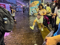Commuters in Tokyo's Shibuya make their way around puddle from sudden heavy rain on Thursday evening. | Nico Phillips