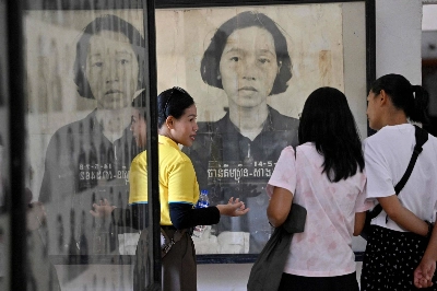 A Cambodian guide (left) gives an explanation about the exhibit as tourists look at portrait photos of victims of the Khmer Rouge regime at the Tuol Sleng Genocide Museum in Phnom Penh on Saturday. A Cambodian guide (left) gives an explanation about the exhibit as tourists look at portrait photos of victims of the Khmer Rouge regime at the Tuol Sleng Genocide Museum in Phnom Penh on Saturday.