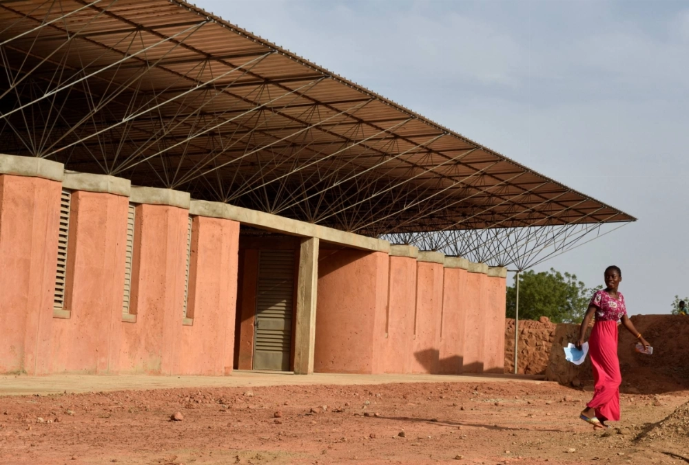 A student leaves the secondary school building built by Pritzker Prize-winning architect Francis Kere, in Kere's home village of Gando, Burkina Faso, on June 3, 2022.  A student leaves the secondary school building built by Pritzker Prize-winning architect Francis Kere, in Kere's home village of Gando, Burkina Faso, on June 3, 2022.