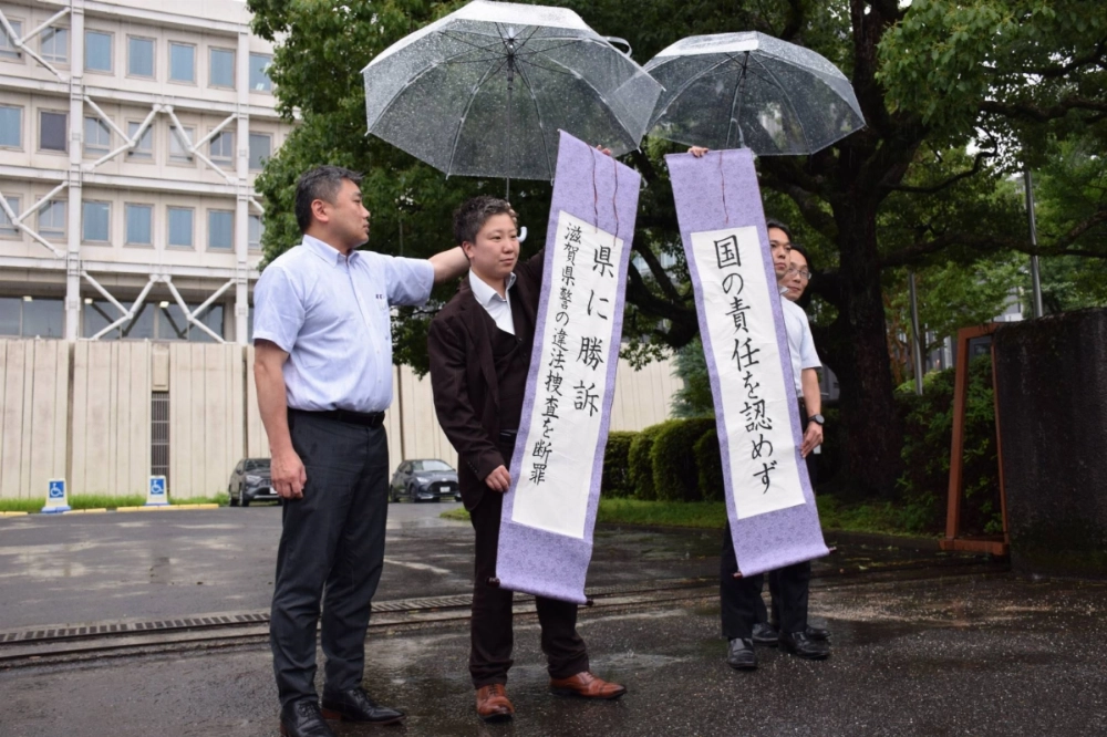 Members of a former nurse’s legal team hold up a sign reading “Victory against the prefecture” after the Otsu District Court ruled in their favor on Thursday.  Members of a former nurse’s legal team hold up a sign reading “Victory against the prefecture” after the Otsu District Court ruled in their favor on Thursday.