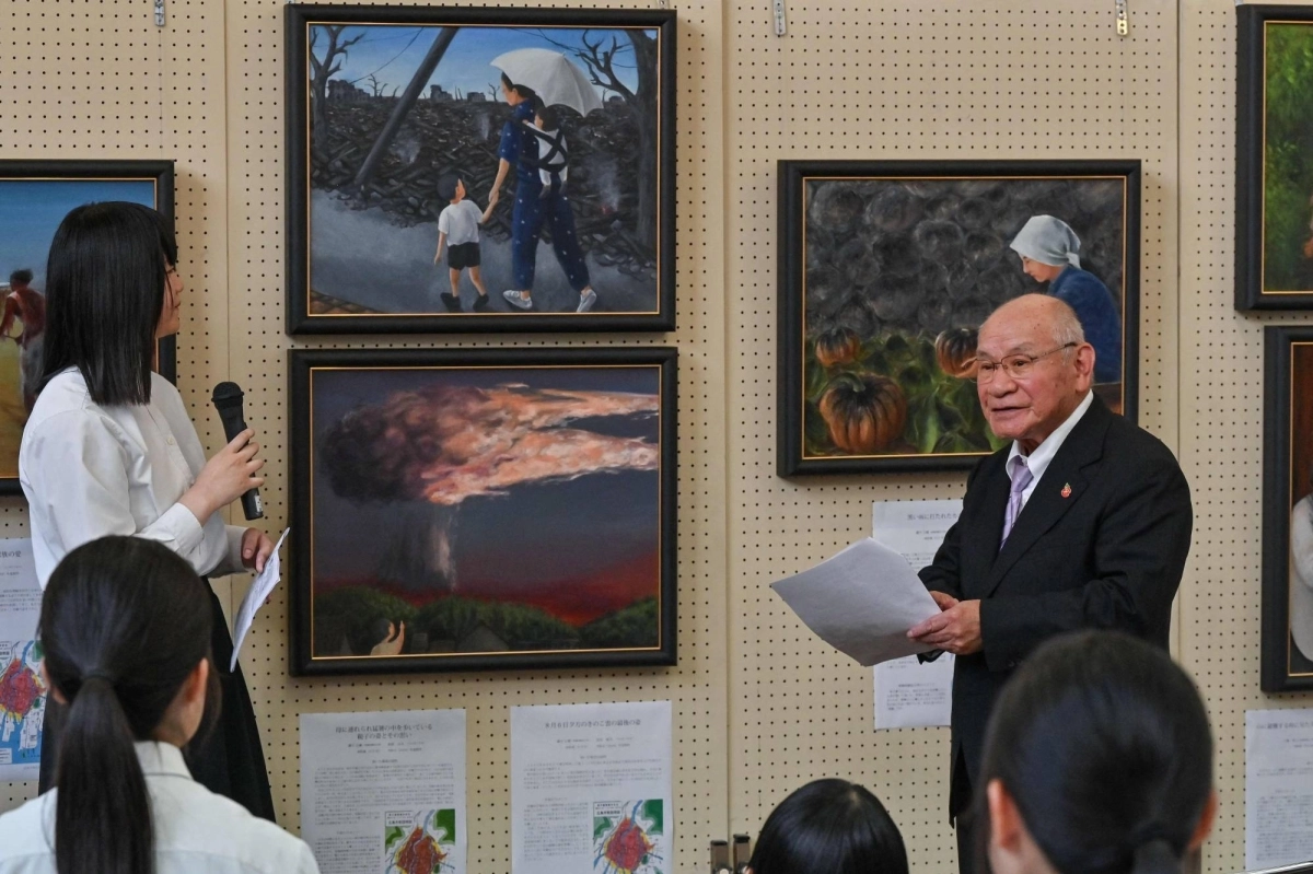 Atomic bomb survivor Masaki Hironaka (right) speaks about a painting (top center) created by student Hana Takasago (left) showing him with his mother in the aftermath of the devastation in 1945, during a press preview of paintings created by students through survivors' testimonies to keep the memories of the bombing relevant for younger generations, at Motomachi High School in the city of Hiroshima on June 27. Atomic bomb survivor Masaki Hironaka (right) speaks about a painting (top center) created by student Hana Takasago (left) showing him with his mother in the aftermath of the devastation in 1945, during a press preview of paintings created by students through survivors' testimonies to keep the memories of the bombing relevant for younger generations, at Motomachi High School in the city of Hiroshima on June 27.