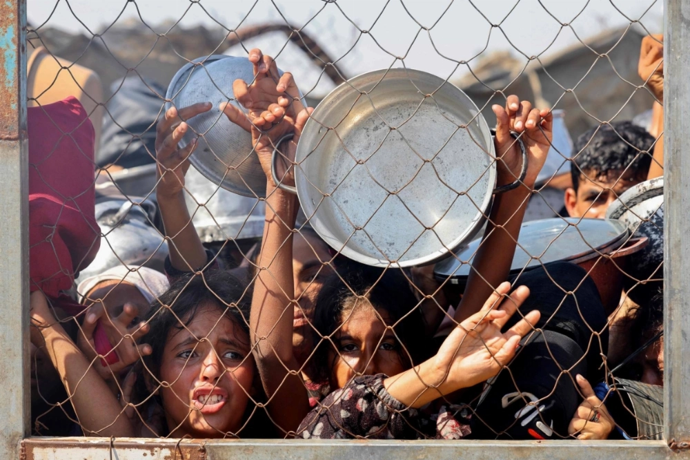 Palestinians, mostly children, attempt to receive a hot meal at a charity kitchen in the Mawasi area of Khan Yunis, in the southern Gaza Strip, on Tuesday. Palestinians, mostly children, attempt to receive a hot meal at a charity kitchen in the Mawasi area of Khan Yunis, in the southern Gaza Strip, on Tuesday.