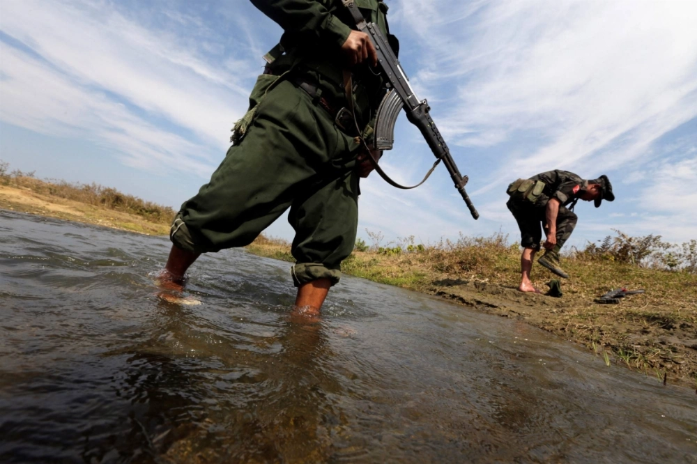 A soldier from the Kachin Independence Army (KIA)  and his comrade cross a stream toward the front line in Laiza, Kachin state, in 2013. A soldier from the Kachin Independence Army (KIA)  and his comrade cross a stream toward the front line in Laiza, Kachin state, in 2013.