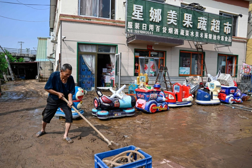 An elderly man clears mud in front of a flooded market after heavy rains at Taishitun village in Miyun district, on the outskirts of Beijing, on Monday. An elderly man clears mud in front of a flooded market after heavy rains at Taishitun village in Miyun district, on the outskirts of Beijing, on Monday.