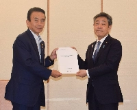 Shizuoka Gov. Yasutomo Suzuki (left) hands a proposal to promote a multicultural society to Deputy Chief Cabinet Secretary Kazuhiko Aoki on Wednesday in Tokyo.  | JIJI