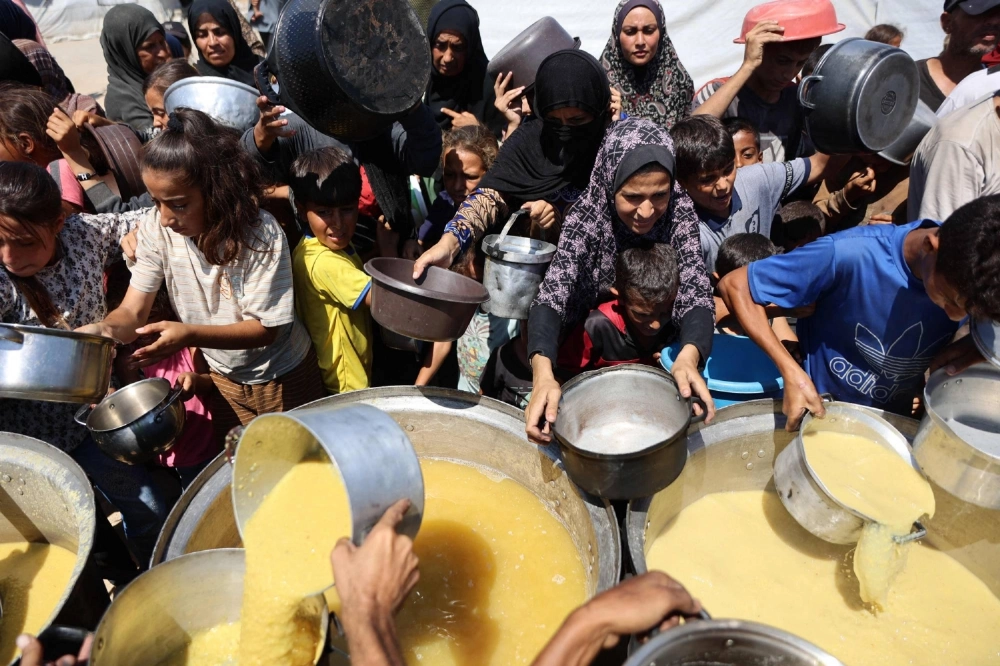 Palestinians receive lentil soup at a food distribution point in Gaza City, in the Gaza Strip, on Friday. Palestinians receive lentil soup at a food distribution point in Gaza City, in the Gaza Strip, on Friday.