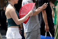 A tourist walks with a paper fan in the Dotonbori area in the city of Osaka on Thursday amid high temperatures. | BLOOMBERG
